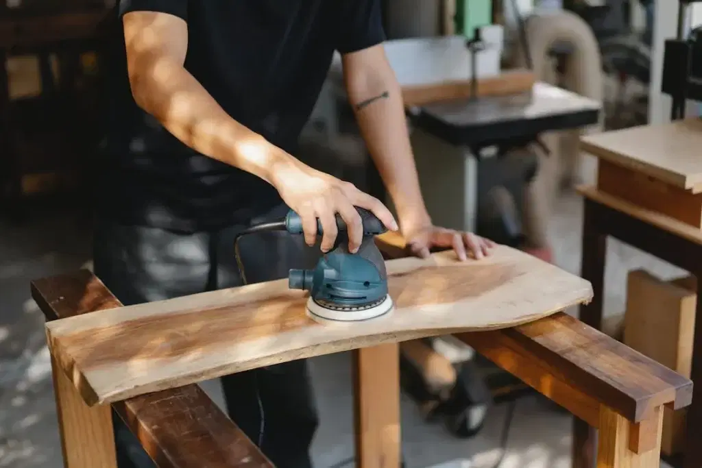 Craftsman polishing wooden board with grinding instrument