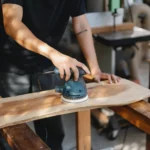 Craftsman polishing wooden board with grinding instrument